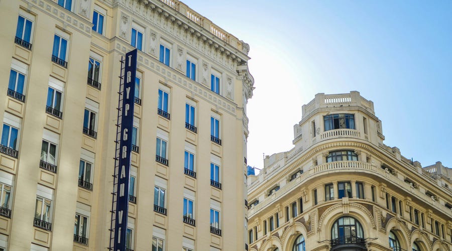 Zwei helle, typisch spanische und prunkvolle Gebäude vor blauem Himmel