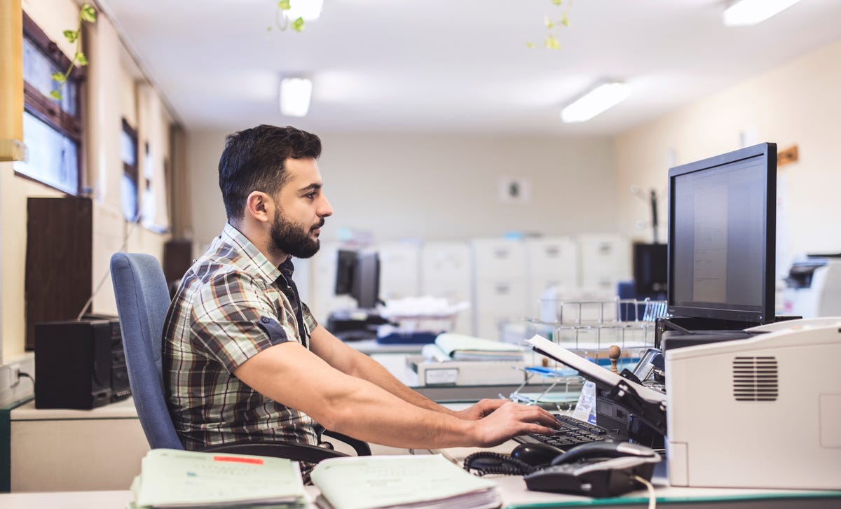 Ein Mann sitzt an seinem Schreibtisch und nimmt von seinem Arbeitsplatz aus an einem deutschen Online-Kurs teil.