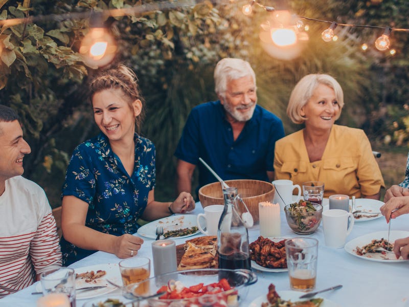 Mehrere Menschen sitzen an einem Tisch, essen und unterhalten sich.