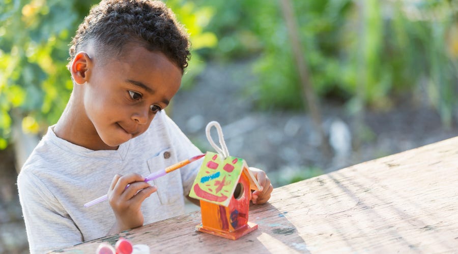 Junge bastelt und bemalt Vogelhaus