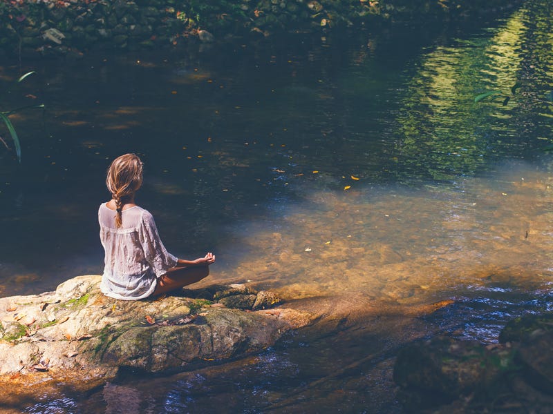 Frau meditiert an einem See
