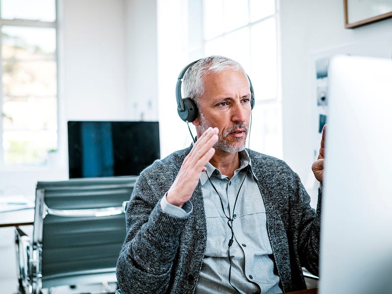 Mann führt mit Headset ein Gespräch am Computer.