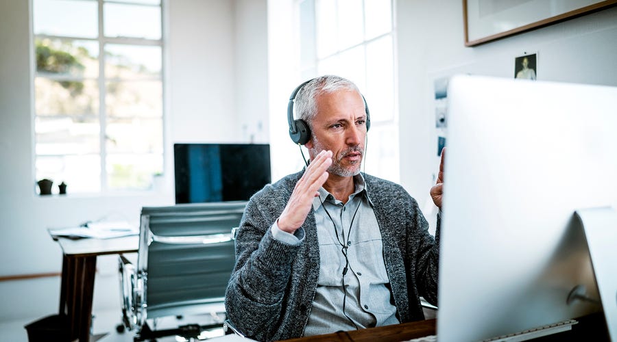 Mann führt mit Headset ein Gespräch am Computer.