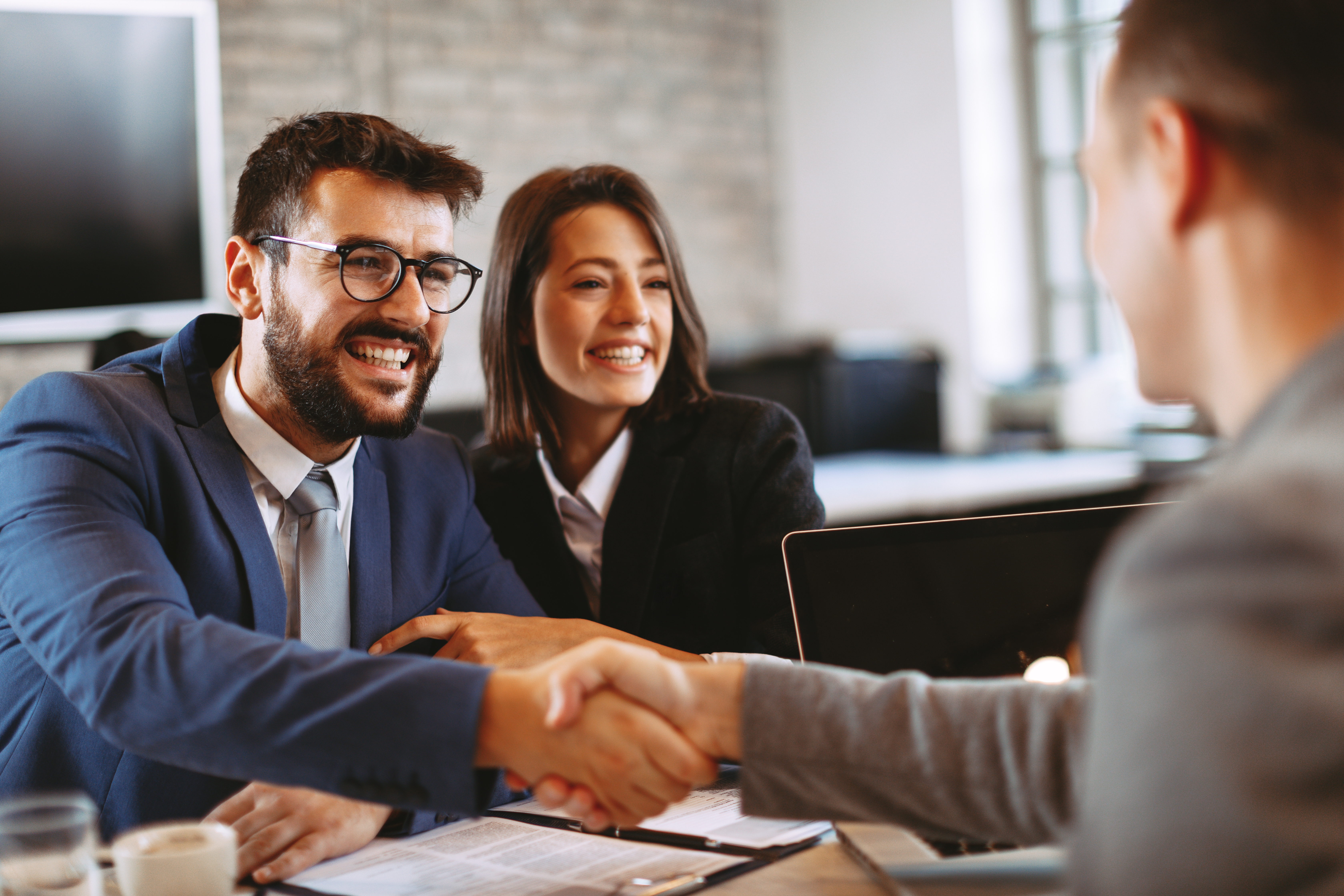 Zwei Männer geben sich über einen Tisch hinweg die Hand.