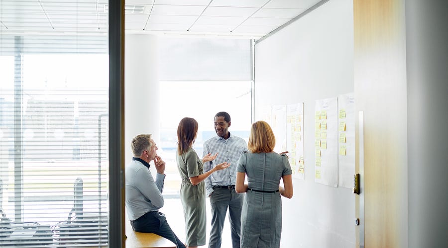 Vier Personen besprechen ein Projekt an einer Wand