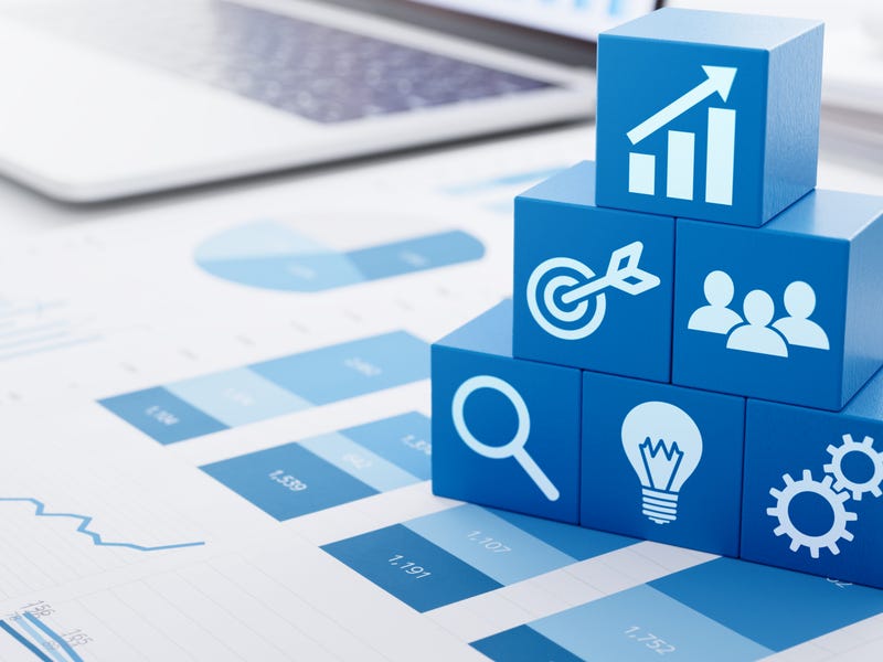 Ein Laptop, Unterlagen, mehrere Würfel mit Symbolen.