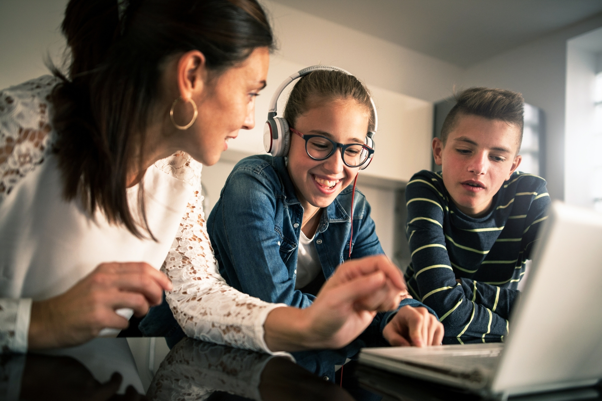Eine Frau und zwei Kinder sitzen gemeinsam vor einem Laptop.