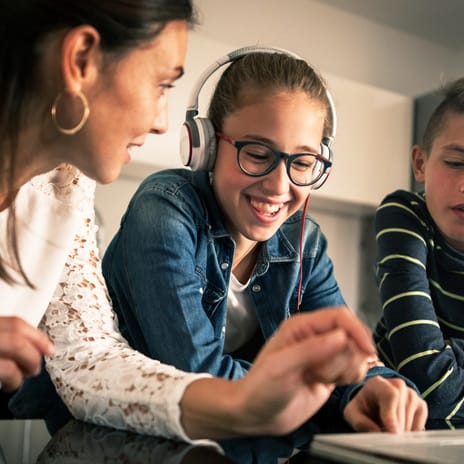 Eine Frau und zwei Kinder sitzen gemeinsam vor einem Laptop.