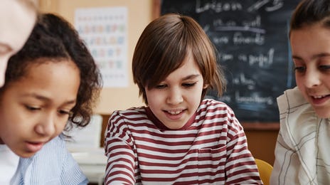 Mehrere Kinder sitzen an einem Tisch zusammen und bearbeiten Aufgaben aus ihrem Sprachkurs.