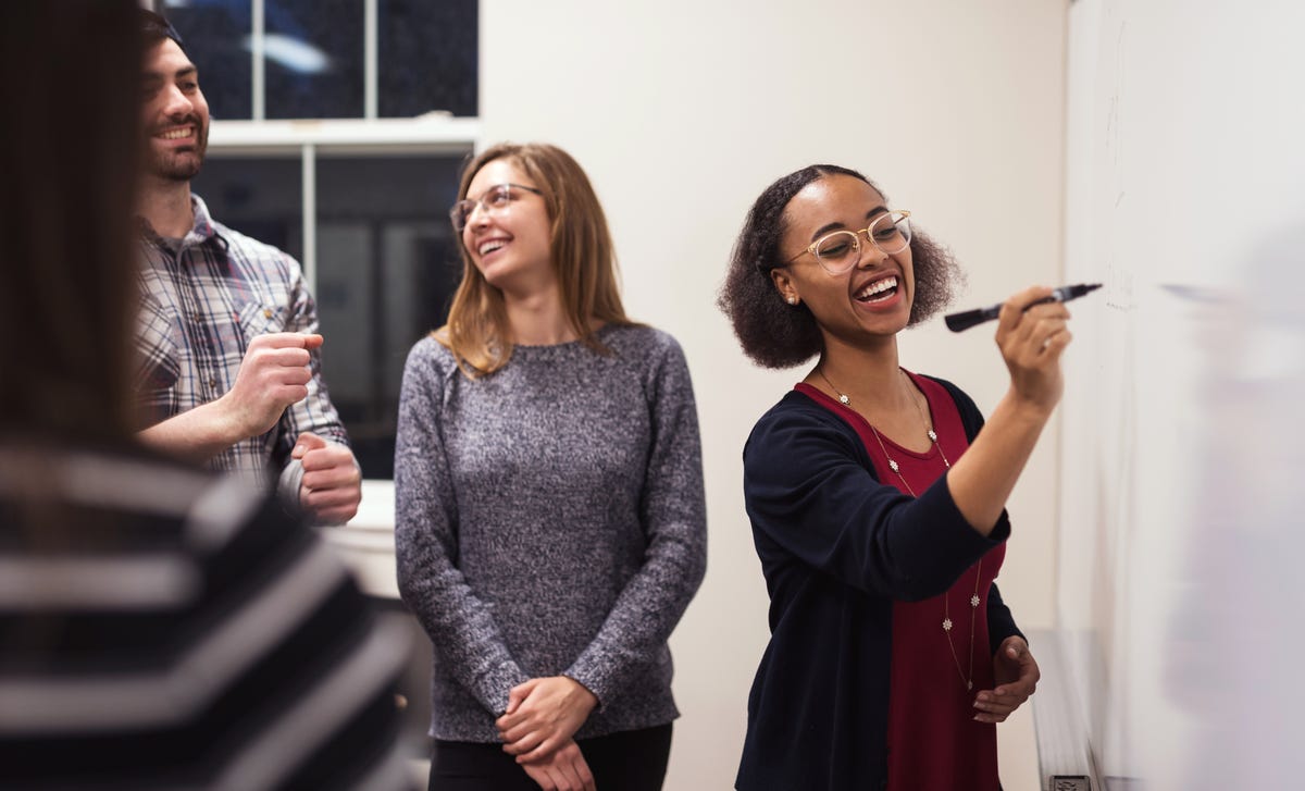 Vier Personen stehen vor einem White-Board.