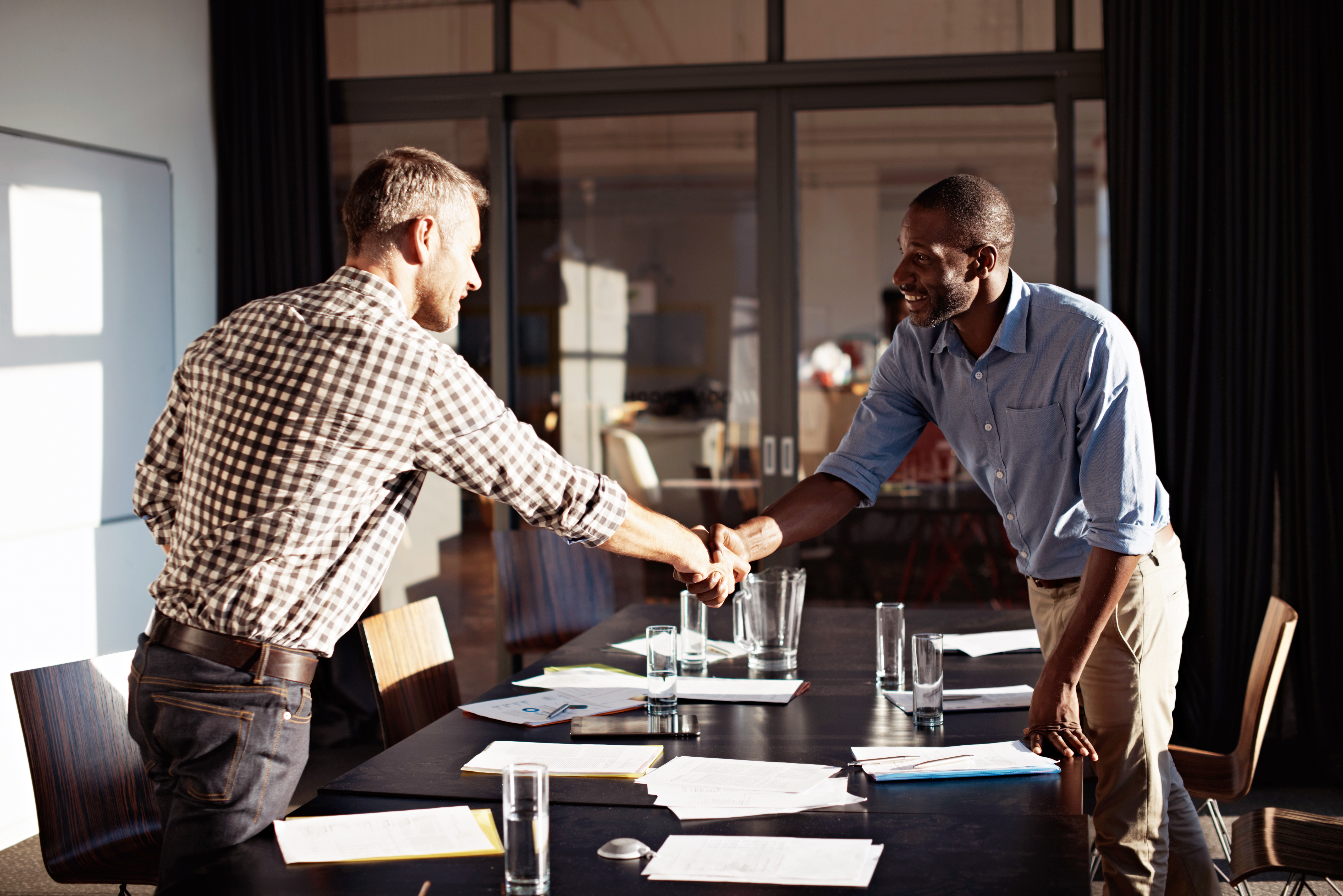 Zwei Männer geben sich am Tisch die Hand.