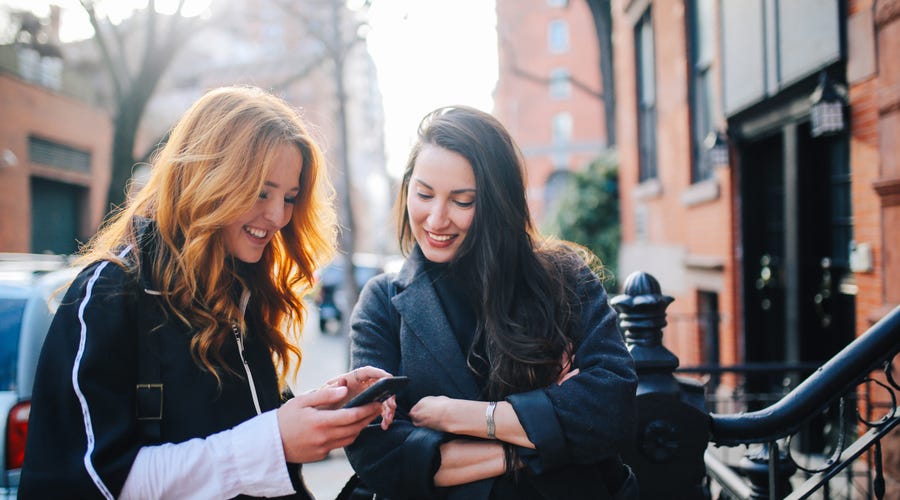 Zwei Frauen schreiben Nachricht am Smartphone