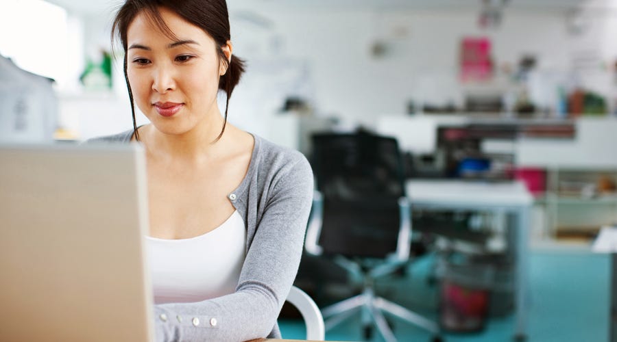 Eine Frau sitzt am Laptop und schreibt.
A women is writing on her laptop.