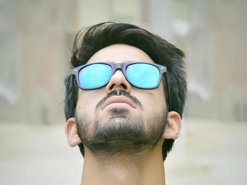 Mann trägt verspiegelte Sonnenbrille und schaut nach oben