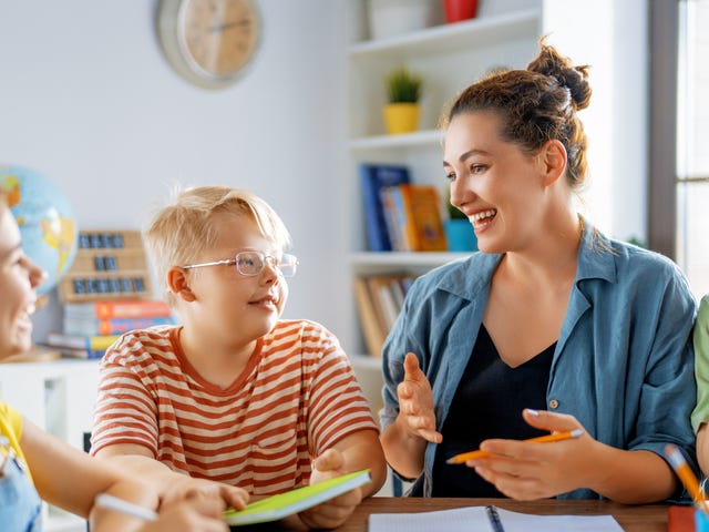 Mehrere Schüler sitzen mit ihrer Trainerin zusammen und besprechen Aufgaben für den Sprachkurs.