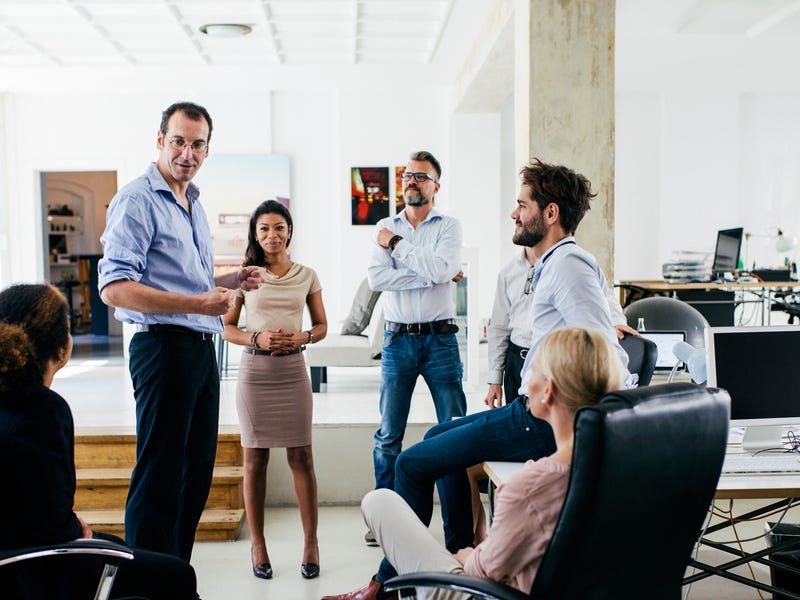 Mitglieder eines Teams stehen im Büro zusammen und besprechen etwas.