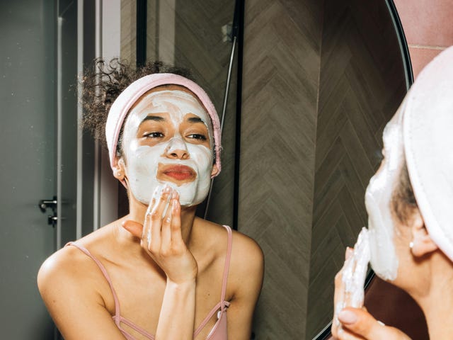 Ein Mädchen steht im Sprachcamp vor dem Spiegel und trägt eine Maske im Gesicht auf.