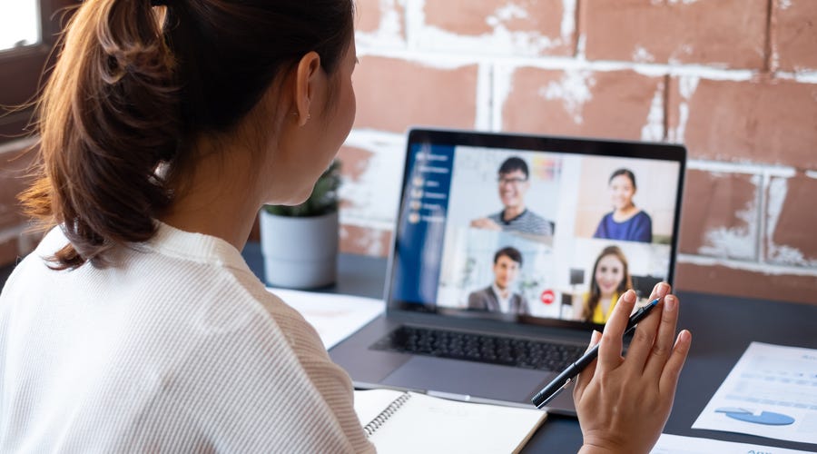 Frau sitzt vor einem Laptop und nimmt an einer Videokonferenz Teil.