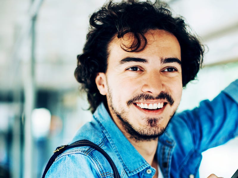 Mann steht mit Handy in der Bahn