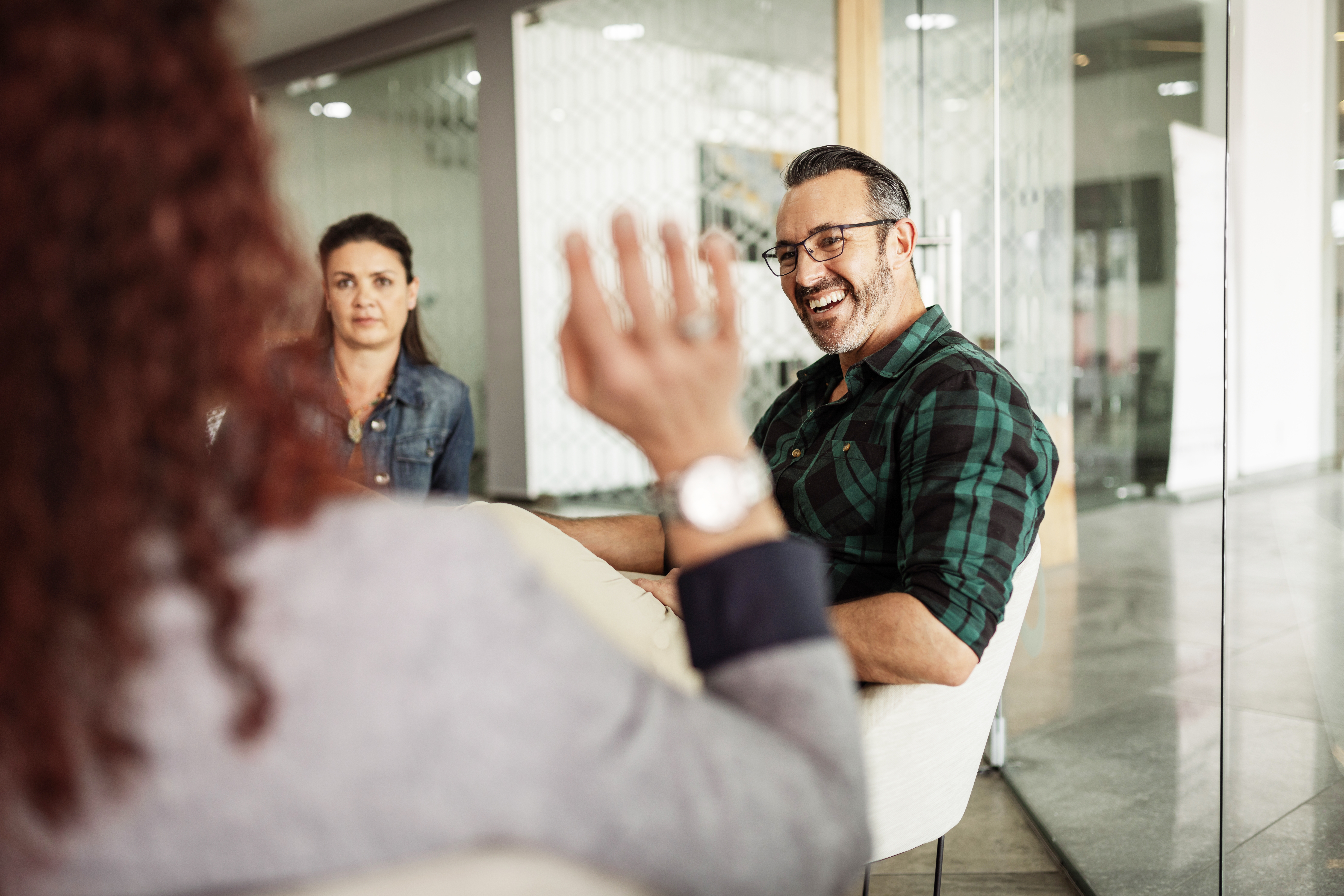 Eine Person winkt zwei anderen Personen zu.