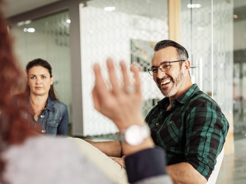 Eine Person winkt zwei anderen Personen zu.