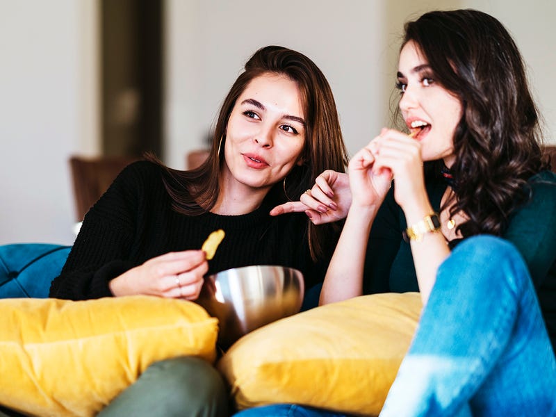 Zwei Frauen sitzen auf dem Sofa und schauen italienische Serien und Filme an