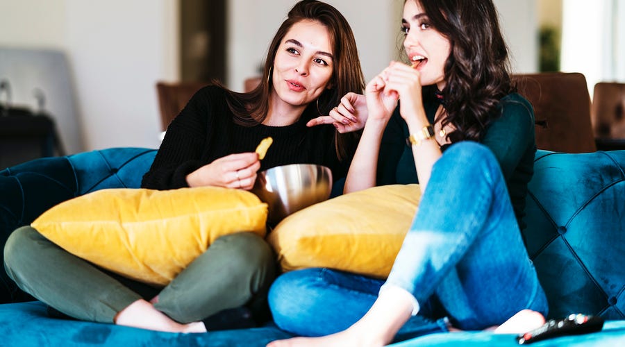 Zwei Frauen sitzen auf dem Sofa und schauen italienische Serien und Filme an