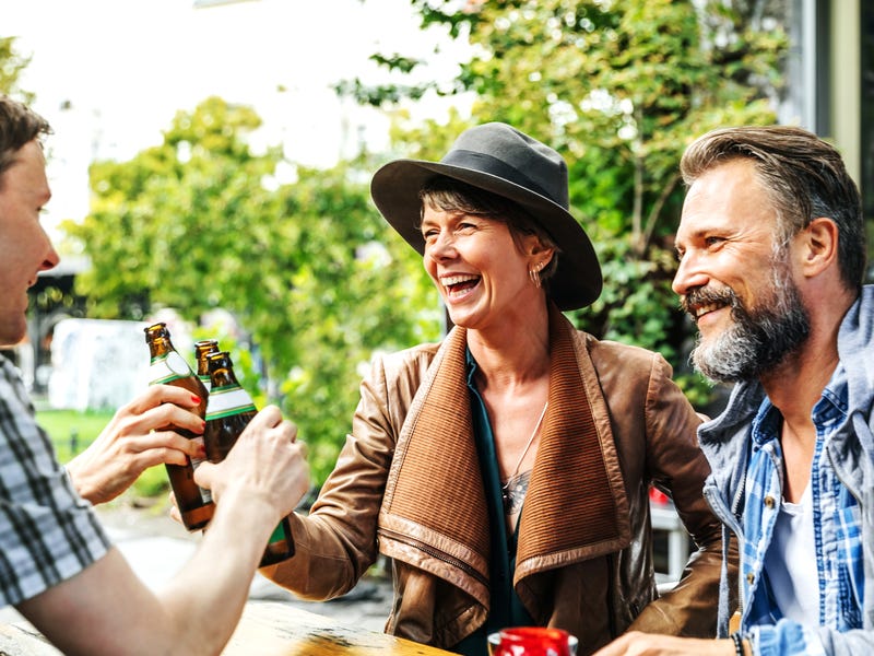 Several people sitting together, cheering with drinks.