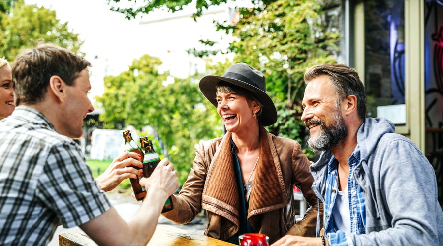 Several people sitting together, cheering with drinks.