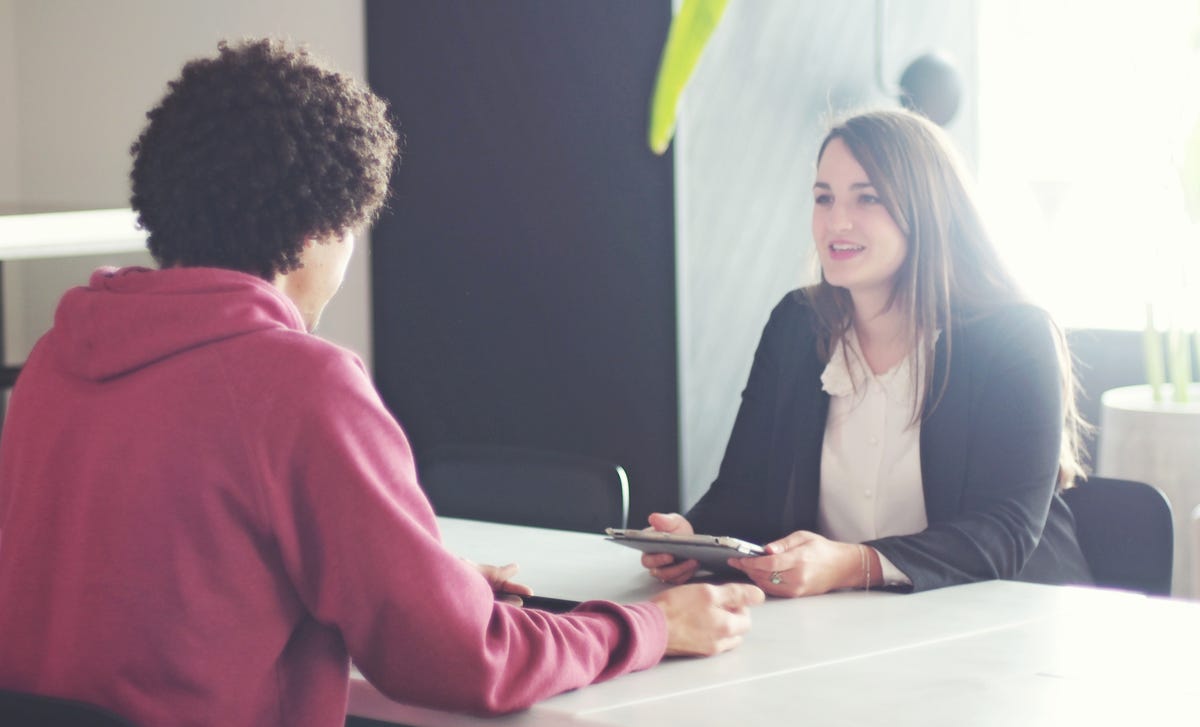 Eine Frau und ein Mann sitzen sich an einem Tisch gegenüber und sprechen.