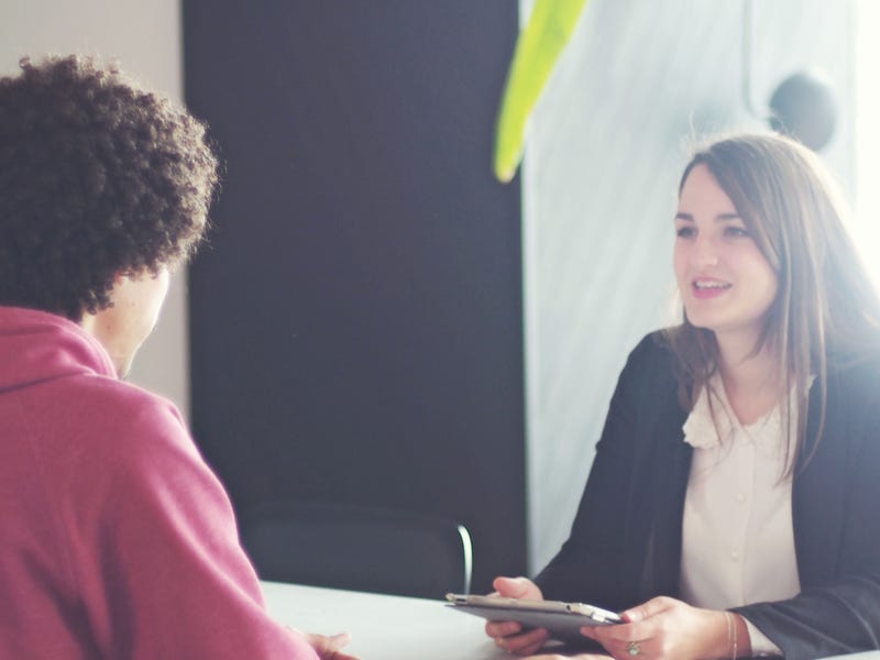 Eine Frau und ein Mann sitzen sich an einem Tisch gegenüber und sprechen.