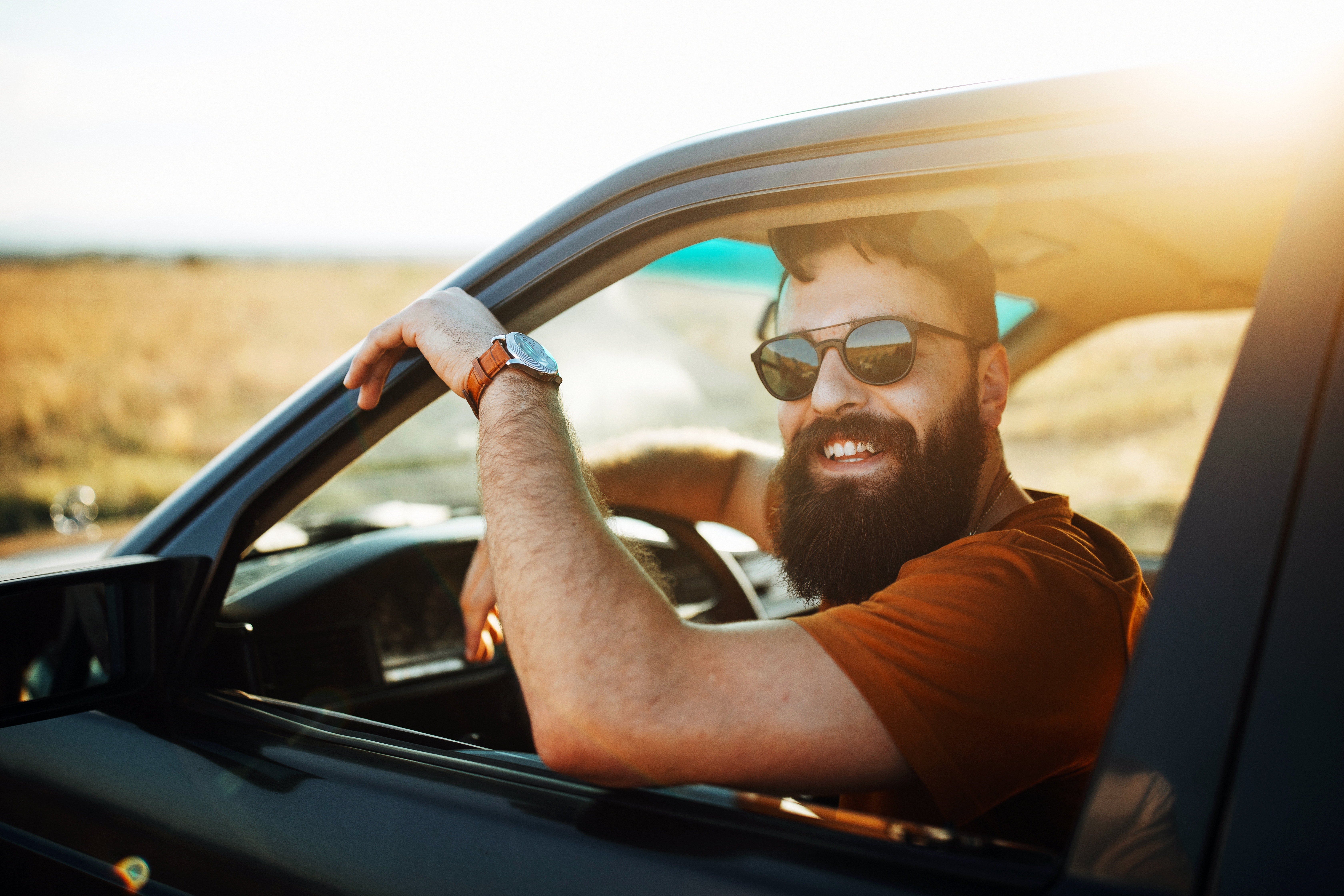 A man in a car, laughing.
Ein Mann sitzt im Auto und lacht.