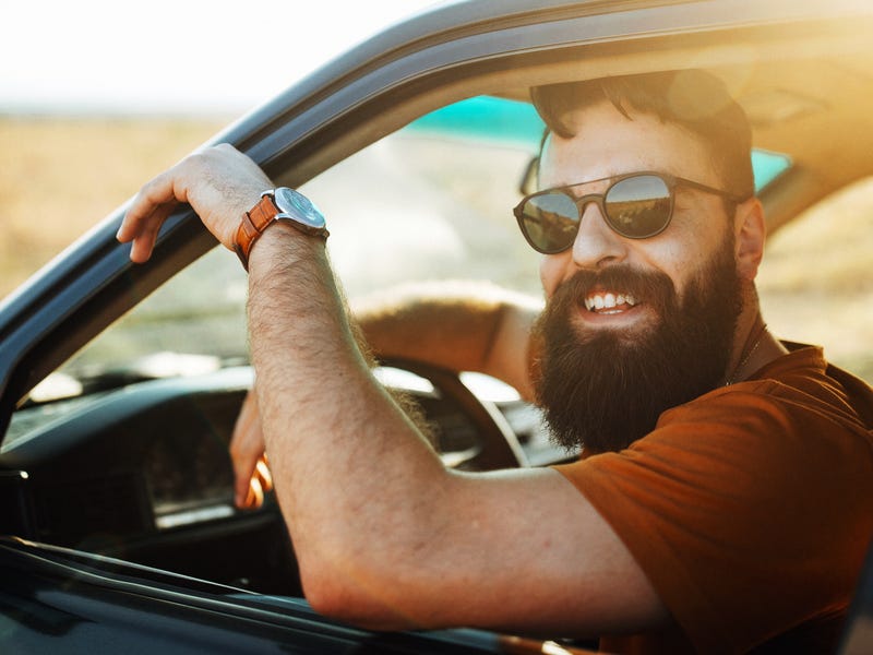A man in a car, laughing.
Ein Mann sitzt im Auto und lacht.