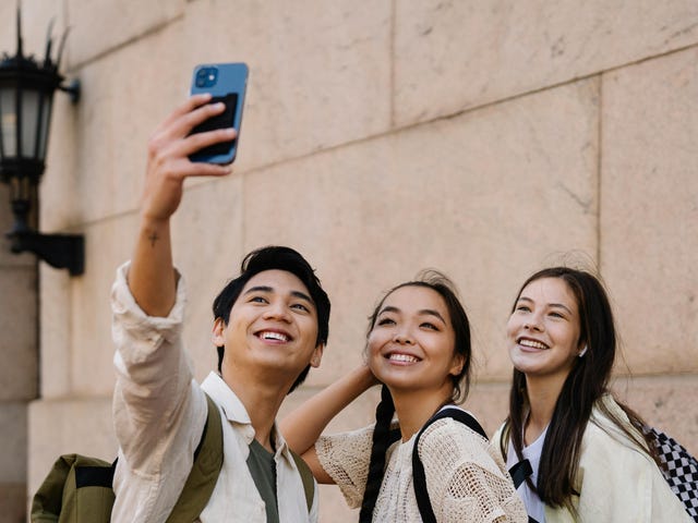 Drei Jugendliche im Sprachcamp sind unterwegs und machen ein Selfie mit ihrem Smartphone.