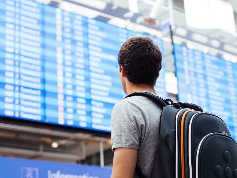 Mann steht am Flughafen vor einer Anzeigentafel