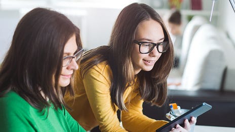 Mutter und Kind schauen gemeinsam auf einen Laptop.