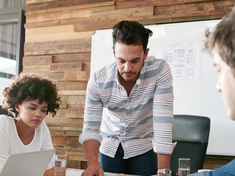 Vier Personen sitzen an einem Tisch und besprechen ein Projekt.