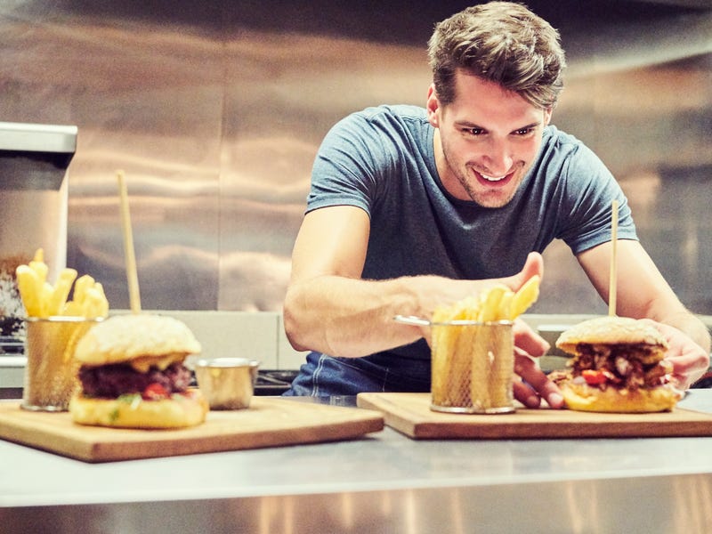 A man presenting burger and pommes frites.