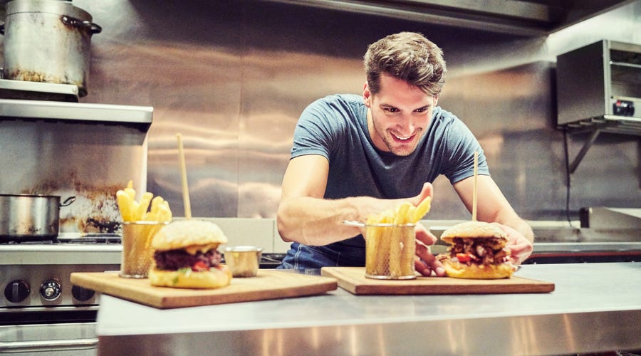 A man presenting burger and pommes frites.
