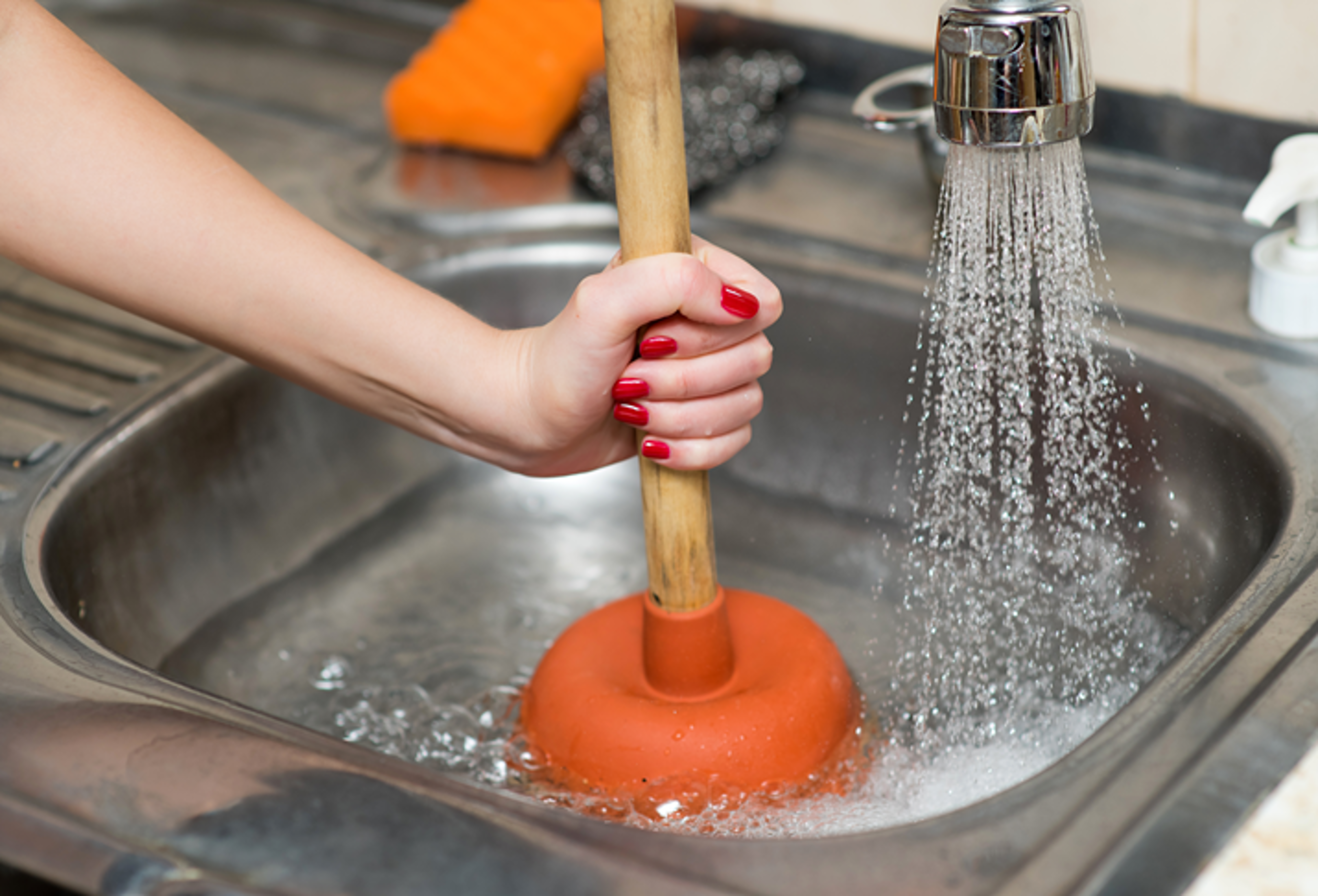 woman using plunger in sink