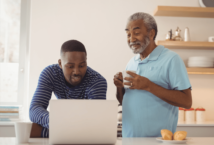 father and son viewing laptop screen