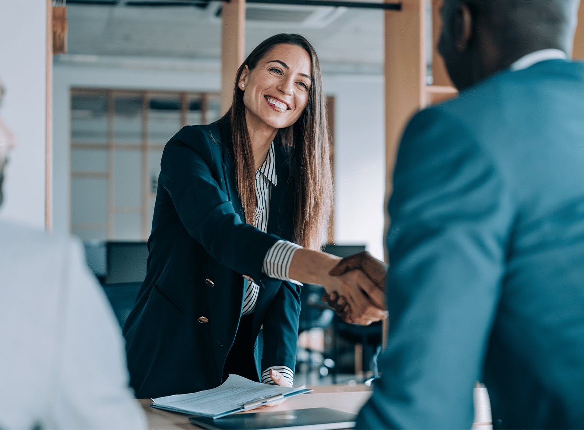 Woman Smiling and Shaking Hands in an Office