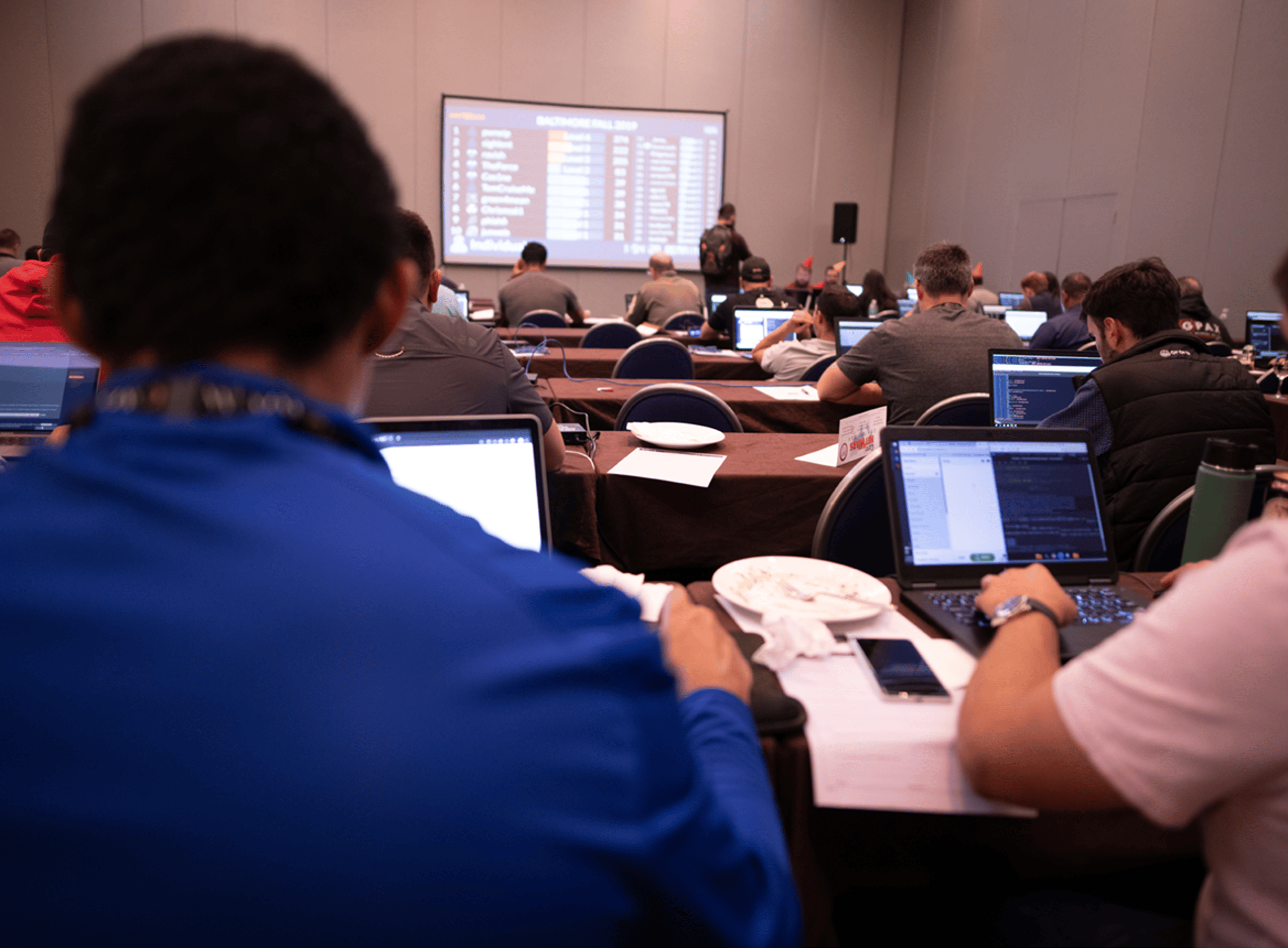 People In a Classroom Using Computers and Looking at Large Screen