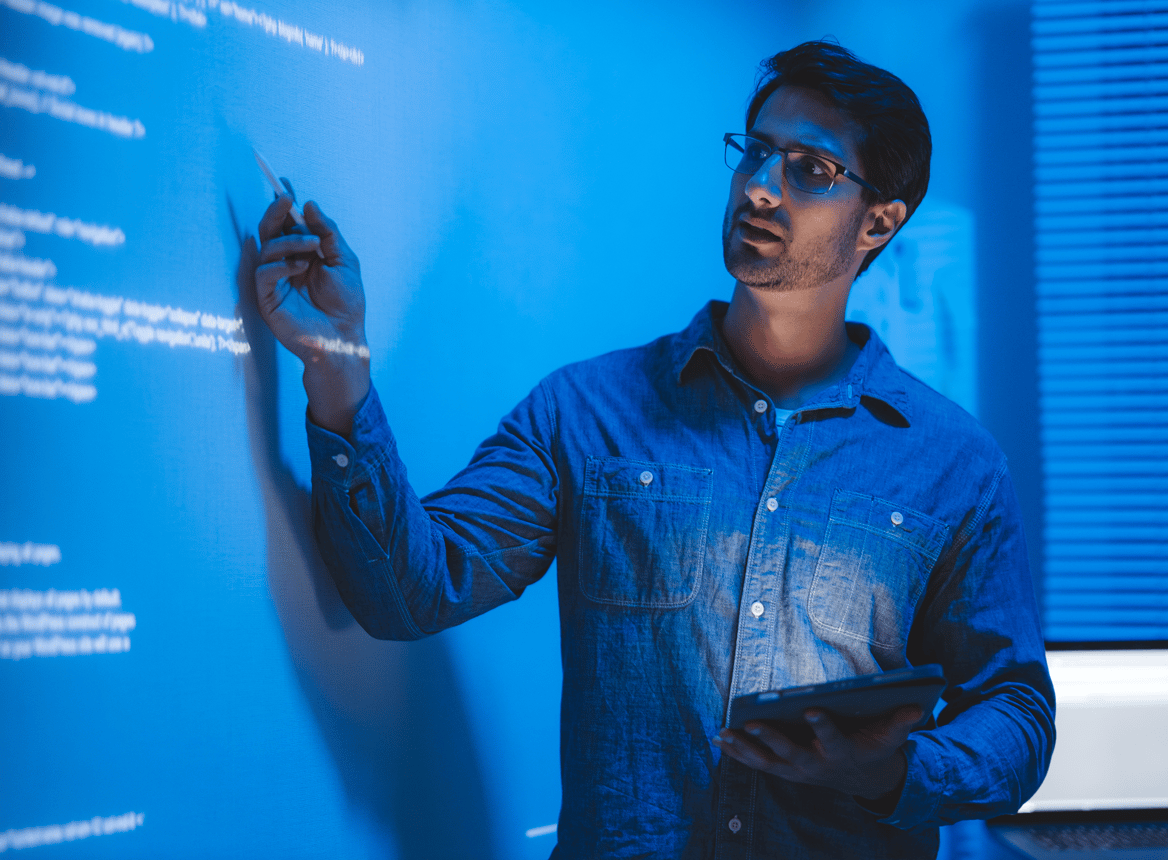 Man Pointing at Text on Smartboard