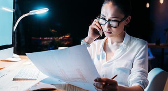 Woman Looking At Paper And Talking On Phone
