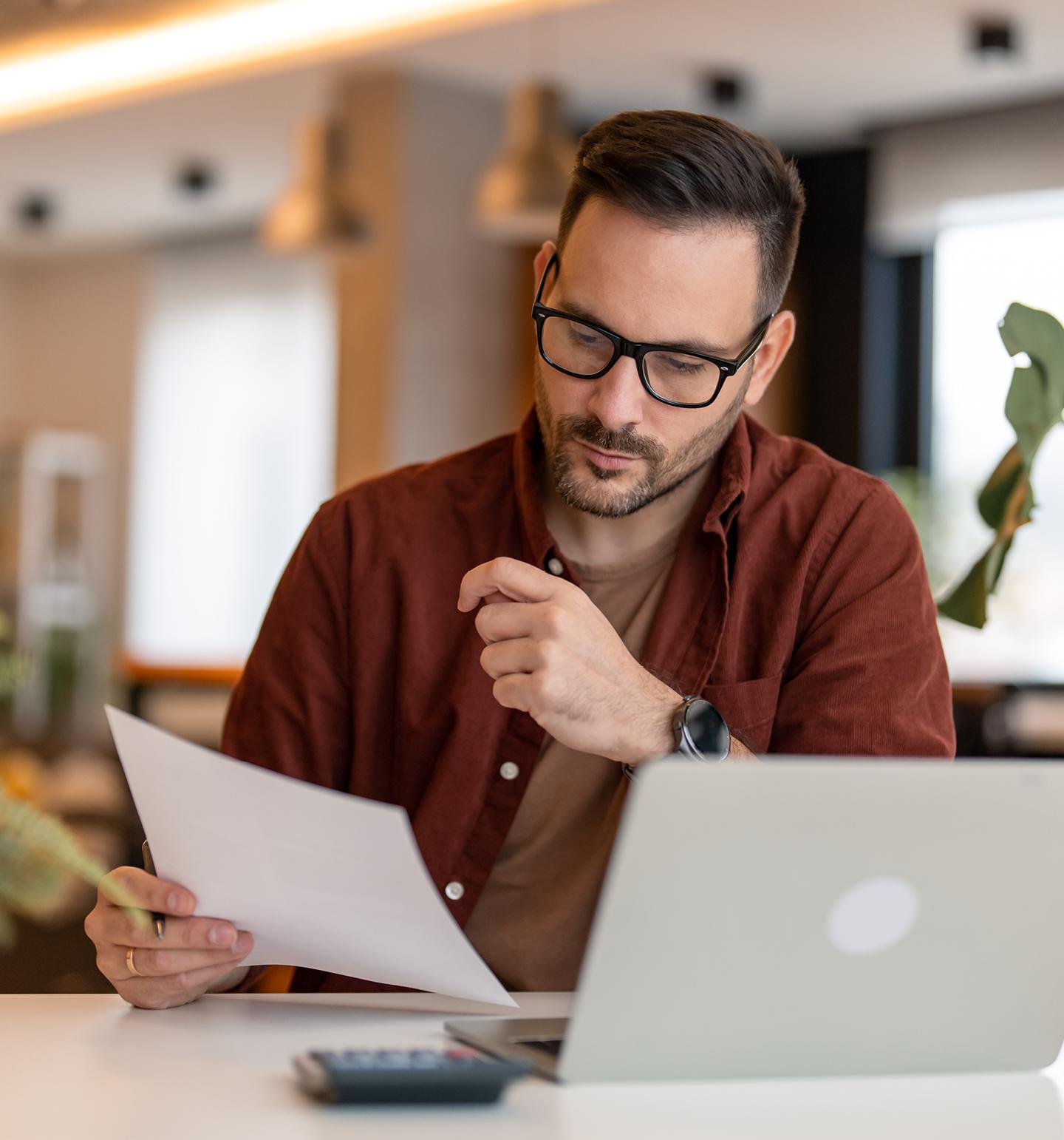 Man Reading a Piece of Paper at Office Desk