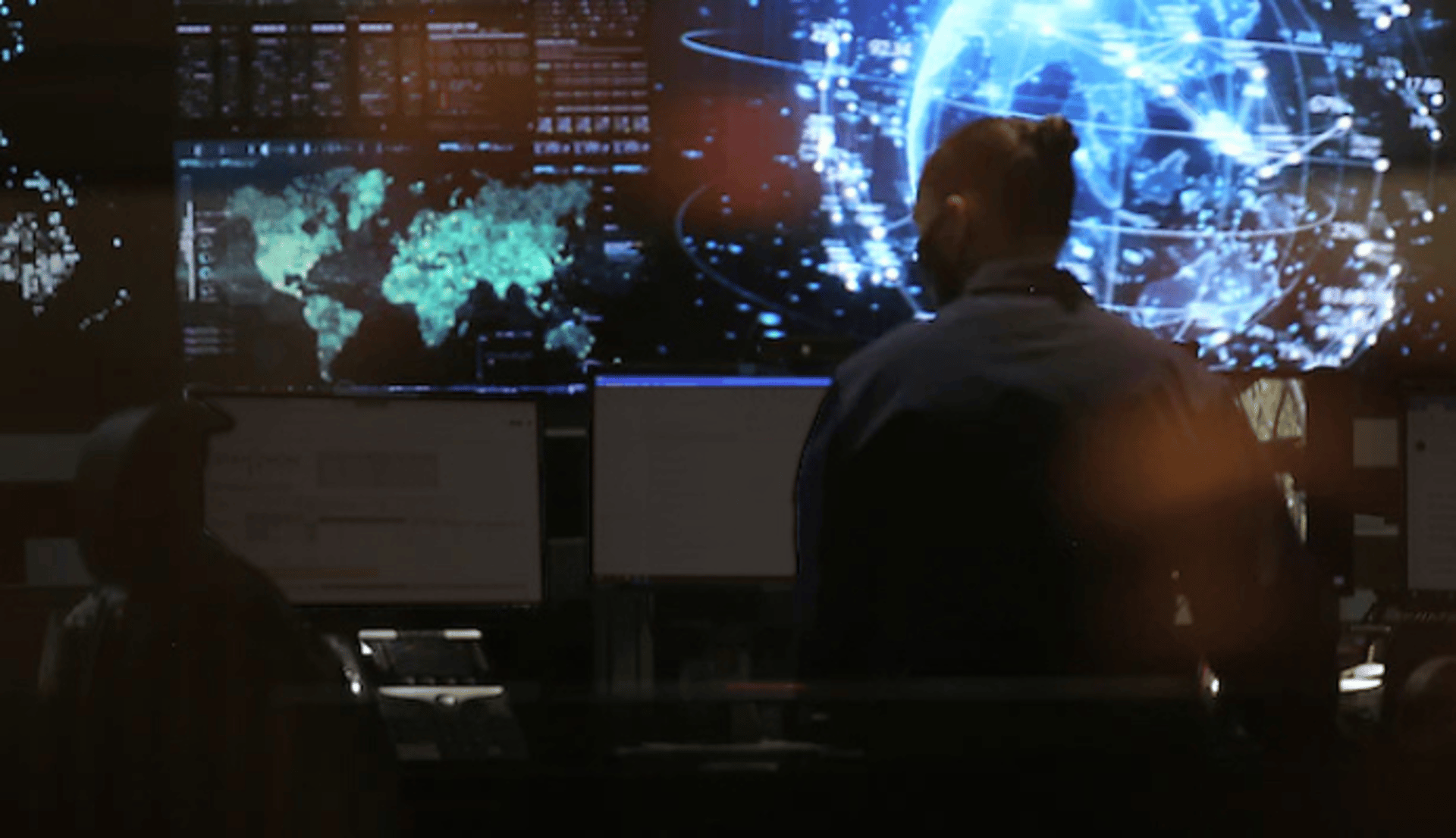 Person in High-Tech War Room Looking at Monitors