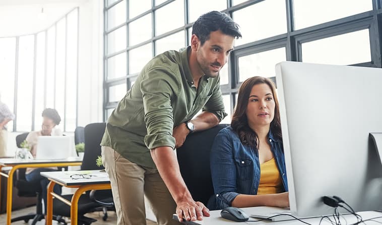Man and Woman Looking at Computer in Office