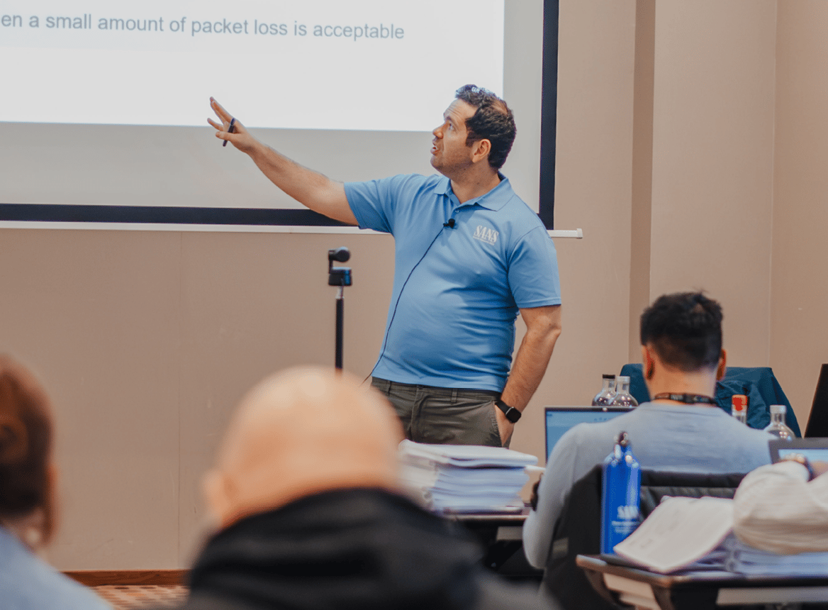 Teacher in Blue Shirt Explaining Material On Large Screen