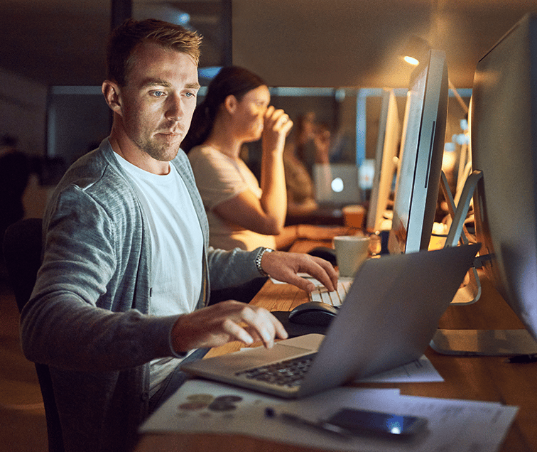 Man Typing at Shared Desk in Office